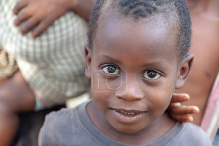 Foto de Xai Xai, Mozambique, abril de 2014: Un primer plano extremo de un joven con penetrantes ojos marrones oscuros ansioso por que un australiano haga su retrato en un pueblo pobre - Imagen libre de derechos