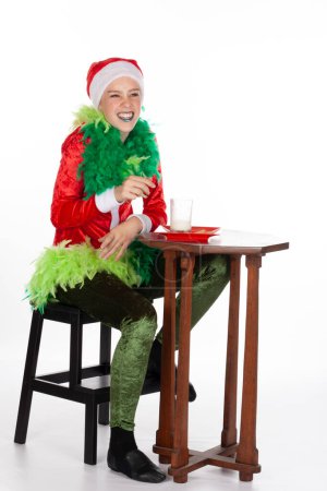 Foto de Retrato completo de una joven con un sombrero de Santa Claus rojo como un grinch con dientes de cojinete de risa, aislado sobre un fondo blanco. Sneering emoción humana expresión facial - Imagen libre de derechos