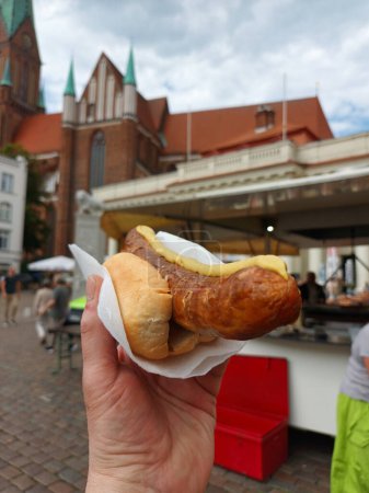 Foto de Salchicha en rollo de pan con mostaza en la plaza del mercado - Imagen libre de derechos