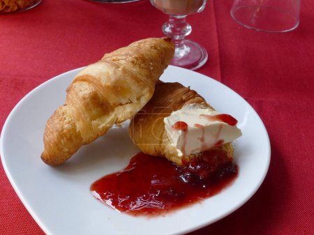 Two croissants, butter and jam on a plate
