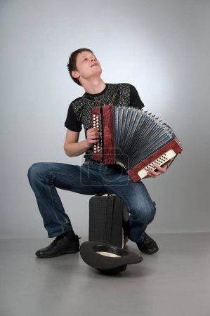 Photo for Man playing accordion and collects money into hat - Royalty Free Image