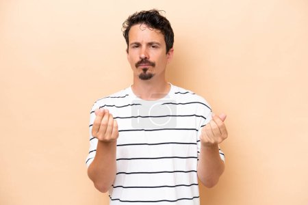 Photo for Young caucasian man isolated on beige background making money gesture but is ruined - Royalty Free Image