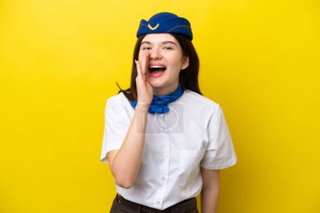 Téléchargez les photos : Hôtesse de l'air femme russe isolé sur fond jaune criant avec la bouche grande ouverte - en image libre de droit