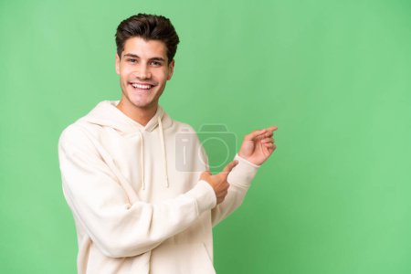 Photo pour Jeune homme beau caucasien sur fond isolé pointant du doigt sur le côté - image libre de droit