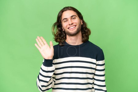 Photo for Young handsome man over isolated background saluting with hand with happy expression - Royalty Free Image