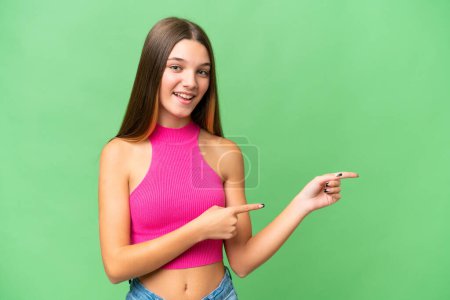 Foto de Adolescente caucásico chica sobre aislado fondo sorprendido y apuntando lado - Imagen libre de derechos