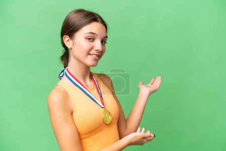 Téléchargez les photos : Adolescente caucasienne avec des médailles sur fond isolé étendant les mains sur le côté pour inviter à venir - en image libre de droit