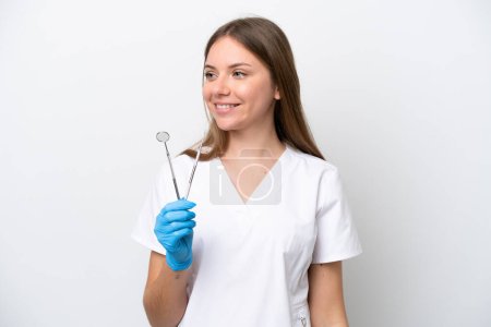 Photo for Dentist woman holding tools isolated on white background looking to the side and smiling - Royalty Free Image