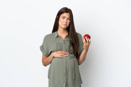 Photo for Young Brazilian woman isolated on white background pregnant and frustrated while holding an apple - Royalty Free Image