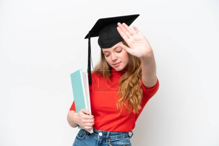 Foto de Joven graduada universitaria aislada sobre fondo blanco haciendo stop gesture y decepcionada - Imagen libre de derechos