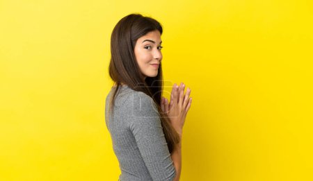 Téléchargez les photos : Jeune femme brésilienne isolée sur fond jaune complotant quelque chose - en image libre de droit