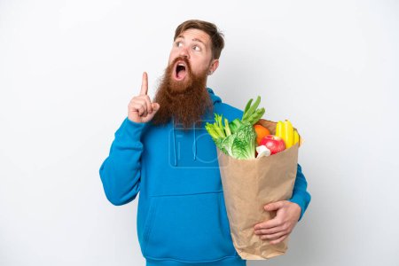 Photo for Redhead man with beard holding a grocery shopping bag isolated on white background thinking an idea pointing the finger up - Royalty Free Image