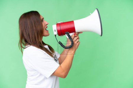 Middle age volunteer woman over isolated chroma key background shouting through a megaphone