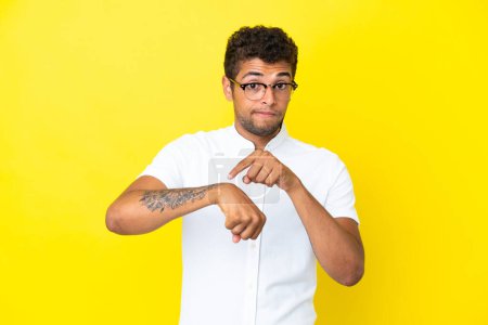 Téléchargez les photos : Jeune bel homme brésilien isolé sur fond jaune faisant le geste d'être en retard - en image libre de droit