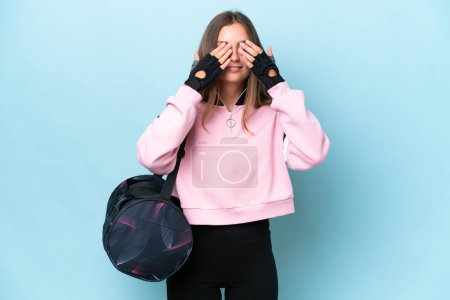 Photo for Young sport woman with sport bag isolated on blue background covering eyes by hands - Royalty Free Image