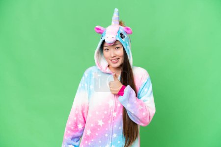 Foto de Young Asian woman with unicorn pajamas over isolated chroma key background giving a thumbs up gesture - Imagen libre de derechos