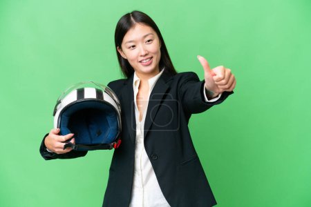 Photo pour Young Asian woman with a motorcycle helmet over isolated chroma key background giving a thumbs up gesture - image libre de droit