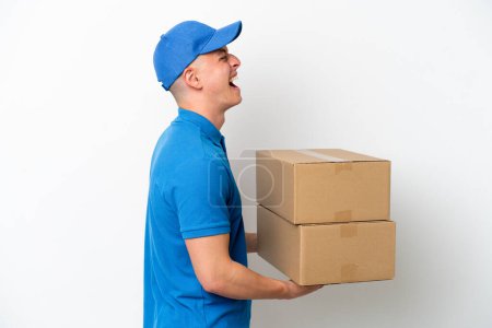 Téléchargez les photos : Young delivery Brazilian man isolated ops white background laughing in lateral position - en image libre de droit