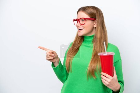 Photo pour Young caucasian woman drinking soda isolated on white background pointing finger to the side and presenting a product - image libre de droit