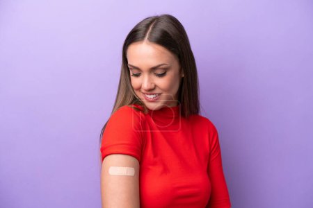 Foto de Young caucasian woman wearing band aid isolated on purple background with happy expression - Imagen libre de derechos