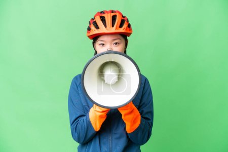 Photo for Young cyclist woman over isolated chroma key background shouting through a megaphone - Royalty Free Image