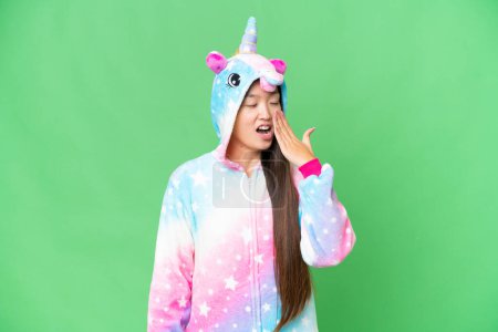 Foto de Young Asian woman with unicorn pajamas over isolated chroma key background yawning and covering wide open mouth with hand - Imagen libre de derechos