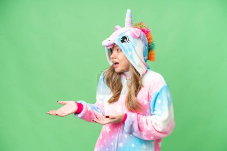 Foto de Chica joven con pijama de unicornio sobre fondo de croma clave aislada con expresión facial sorpresa - Imagen libre de derechos