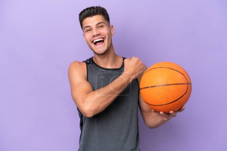 Téléchargez les photos : Jeune femme caucasienne joueur de basket-ball homme isolé sur fond violet célébrant une victoire - en image libre de droit