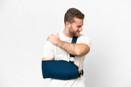 Téléchargez les photos : Young handsome blonde man with broken arm and wearing a sling over isolated white background suffering from pain in shoulder for having made an effort - en image libre de droit