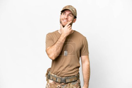 Foto de Military with dog tag over isolated white background thinking an idea while looking up - Imagen libre de derechos