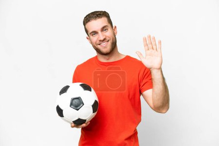 Foto de Guapo joven jugador de fútbol hombre sobre fondo blanco aislado saludando con la mano con expresión feliz - Imagen libre de derechos