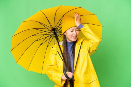 Téléchargez les photos : Young Asian woman with rainproof coat and umbrella over isolated chroma key background has realized something and intending the solution - en image libre de droit