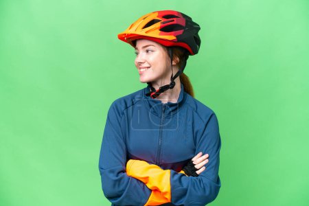 Foto de Joven ciclista mujer sobre aislado croma clave fondo buscando lado - Imagen libre de derechos