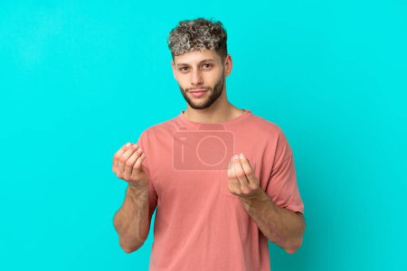 Téléchargez les photos : Young handsome caucasian man isolated on blue background making money gesture but is ruined - en image libre de droit