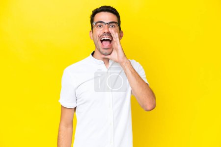 Photo pour Jeune homme beau sur fond jaune isolé criant avec la bouche grande ouverte - image libre de droit
