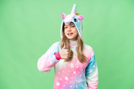 Foto de Chica joven con pijama de unicornio sobre fondo de croma clave aislado dando un gesto pulgar hacia arriba - Imagen libre de derechos