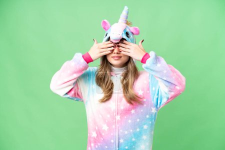 Foto de Chica joven con pijama de unicornio sobre fondo de croma clave aislada que cubre los ojos por las manos - Imagen libre de derechos