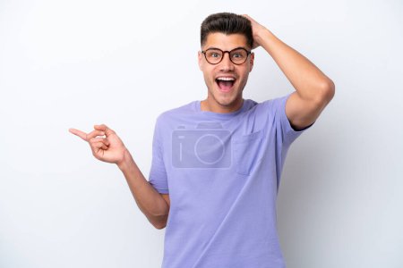 Young caucasian man isolated on white background surprised and pointing finger to the side