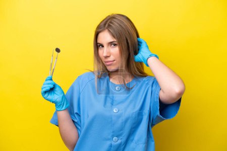 Photo for Dentist caucasian woman holding tools isolated on yellow background having doubts - Royalty Free Image
