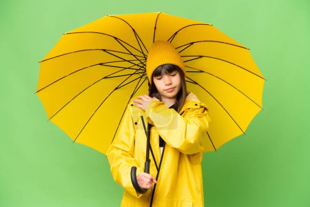 Photo for Little girl with rainproof coat and umbrella over isolated chroma key background suffering from pain in shoulder for having made an effort - Royalty Free Image
