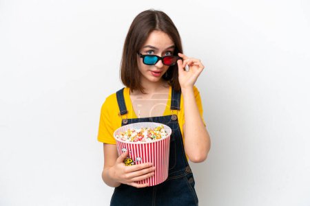 Foto de Young Ukrainian woman isolated on white background surprised with 3d glasses and holding a big bucket of popcorns - Imagen libre de derechos
