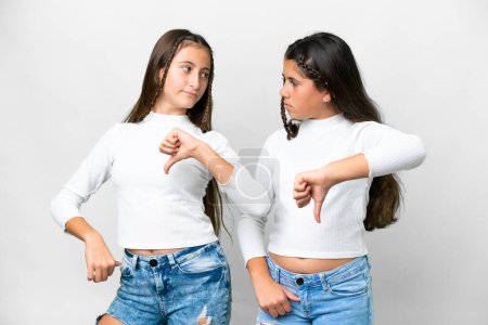 Friends girls over isolated white background showing thumb down sign with negative expression