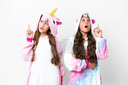 Foto de Amigos chicas con pijama de unicornio sobre fondo blanco aislado pensando en una idea apuntando con el dedo hacia arriba - Imagen libre de derechos