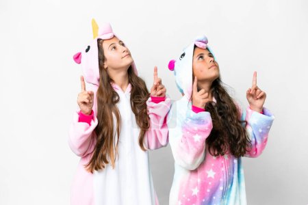 Foto de Amigos chicas con pijama de unicornio sobre fondo blanco aislado señalando con el dedo índice una gran idea - Imagen libre de derechos