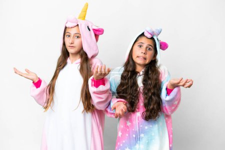 Foto de Amigos chicas con pijamas unicornio sobre fondo blanco aislado infeliz y frustrado con algo porque no entender algo - Imagen libre de derechos