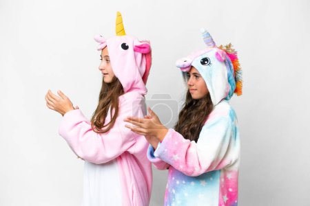 Foto de Amigos chicas con pijama de unicornio sobre fondo blanco aislado aplaudiendo después de la presentación en una conferencia - Imagen libre de derechos