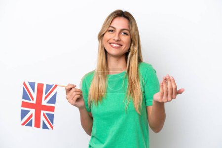 Téléchargez les photos : Jeune femme uruguayenne tenant un drapeau britannique isolé sur fond blanc invitant à venir avec la main. Heureux que tu sois venu - en image libre de droit