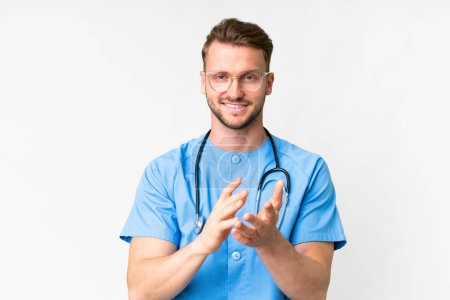 Photo for Young nurse man over isolated white background applauding after presentation in a conference - Royalty Free Image