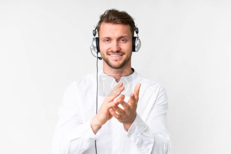 Telemarketer caucasian man working with a headset over isolated white background applauding after presentation in a conference