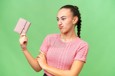 Photo for Young Arab woman holding a wallet over isolated background with sad expression - Royalty Free Image